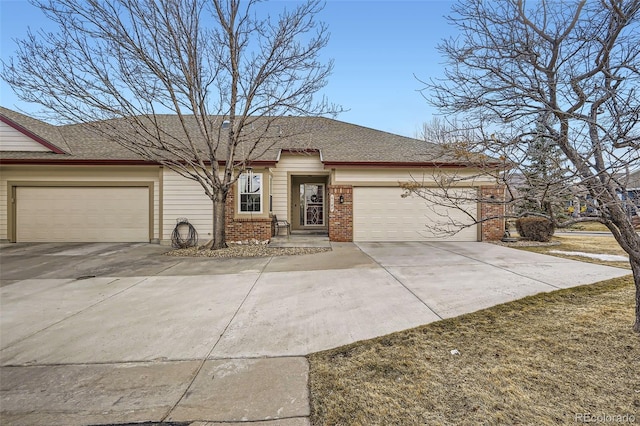 view of front of property featuring an attached garage, a shingled roof, concrete driveway, and brick siding