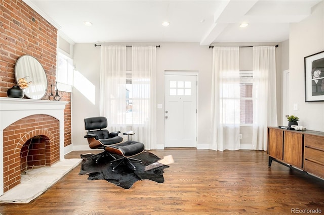 living area featuring a fireplace, baseboards, wood finished floors, and beamed ceiling