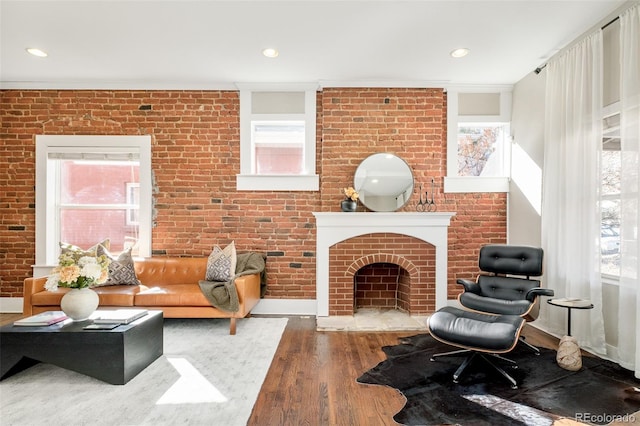 sitting room with brick wall, a wealth of natural light, and wood finished floors