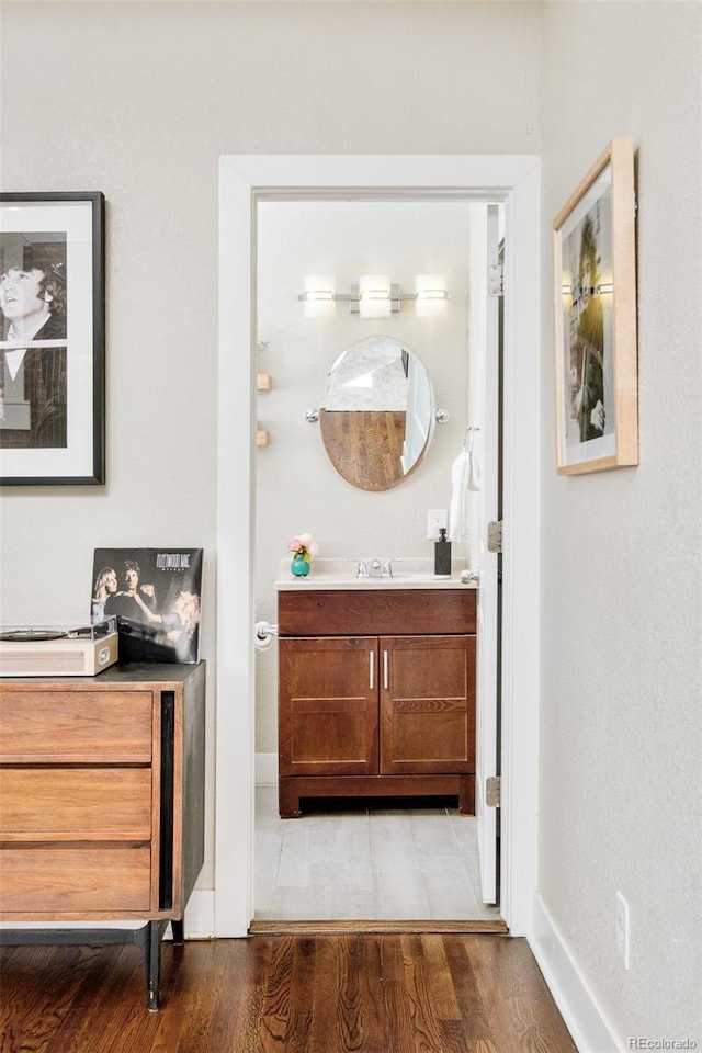 bathroom with wood finished floors, vanity, and baseboards