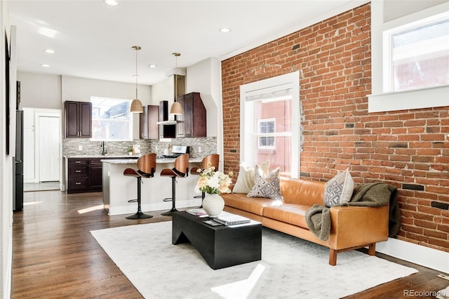 living area featuring dark wood-type flooring, recessed lighting, and brick wall