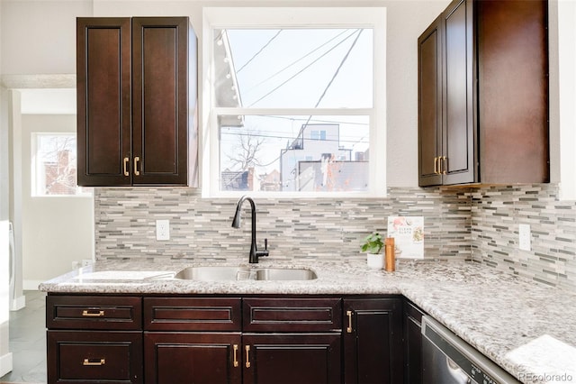 kitchen featuring a sink, dark brown cabinets, light stone countertops, dishwasher, and tasteful backsplash