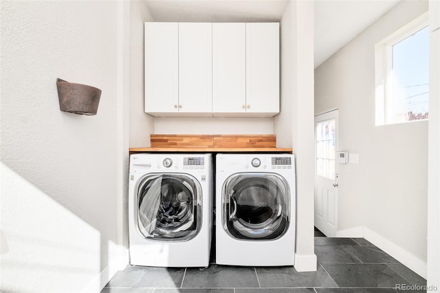 laundry room with separate washer and dryer, dark tile patterned floors, cabinet space, and baseboards