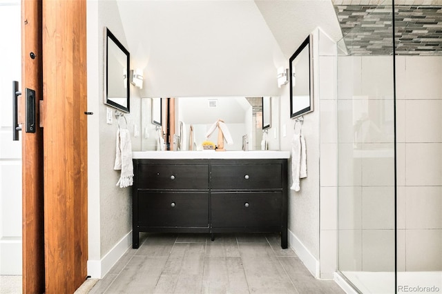 full bathroom with a tile shower, vanity, and baseboards