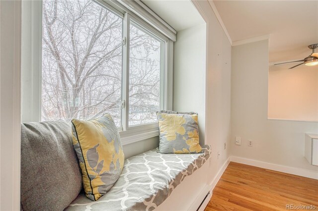 sitting room with ornamental molding, light wood-type flooring, ceiling fan, and baseboards