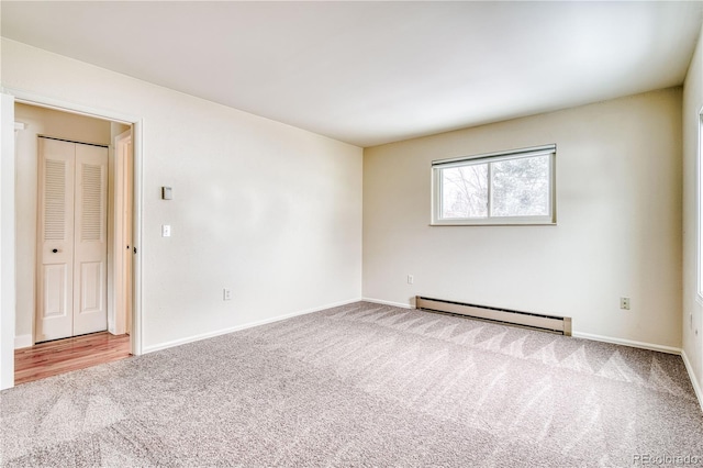 carpeted spare room featuring a baseboard radiator and baseboards