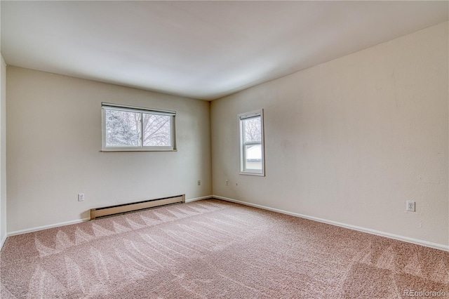 empty room with a baseboard radiator, light colored carpet, and baseboards