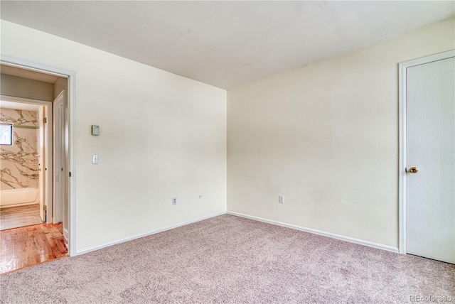 empty room featuring light carpet and baseboards