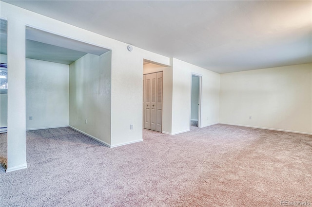 spare room featuring light carpet and baseboards