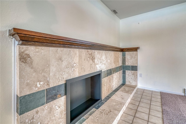 interior space featuring a tile fireplace, visible vents, and baseboards