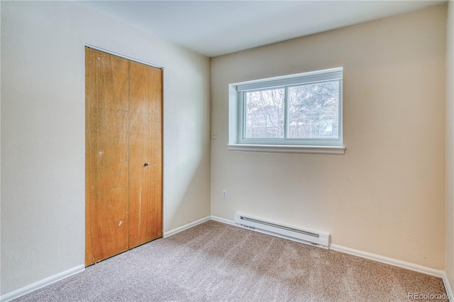 unfurnished bedroom with carpet floors, a baseboard radiator, a closet, and baseboards