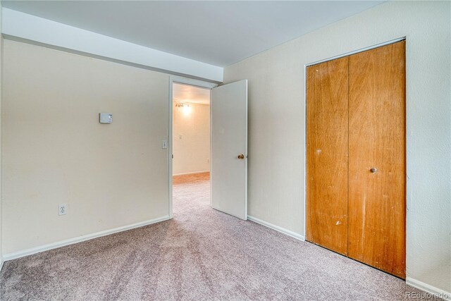 unfurnished bedroom featuring carpet floors, a closet, and baseboards