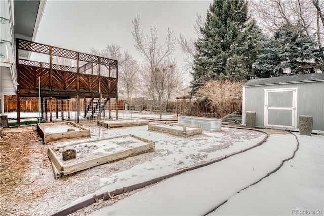 yard layered in snow with an outbuilding, a garden, fence, and a storage unit