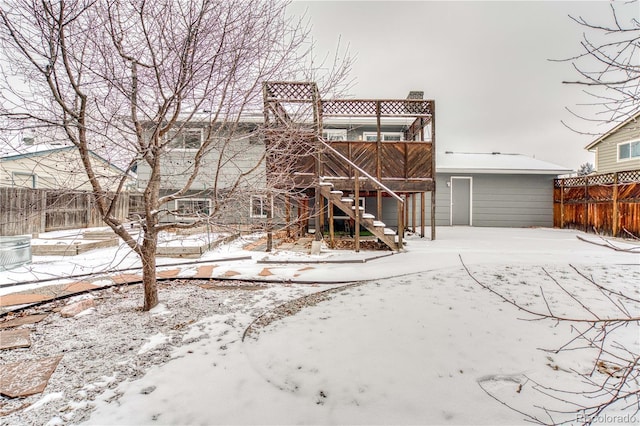 snow covered house featuring stairway and fence