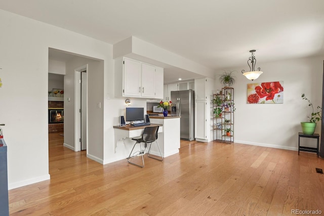 10310 E Jewell Ave Unit 55, Aurora, CO 80247 - kitchen featuring stainless steel fridge with ice dispenser, a peninsula, white cabinetry, light wood-style floors, and a breakfast bar