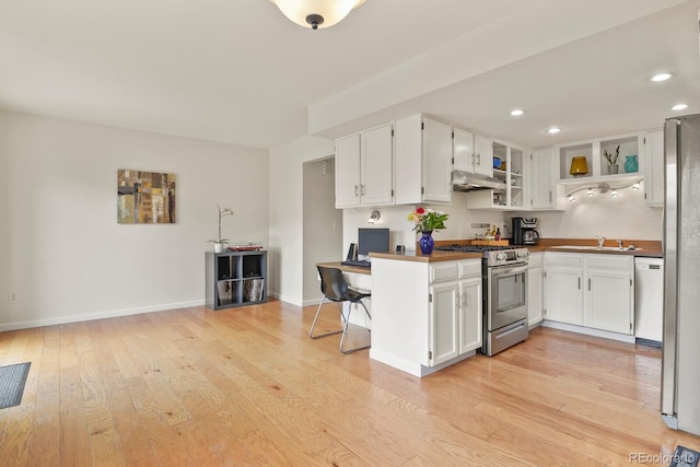 10310 E Jewell Ave Unit 55, Aurora, CO 80247 - kitchen featuring stainless steel appliances, under cabinet range hood, a sink, light wood finished floors, and white cabinetry