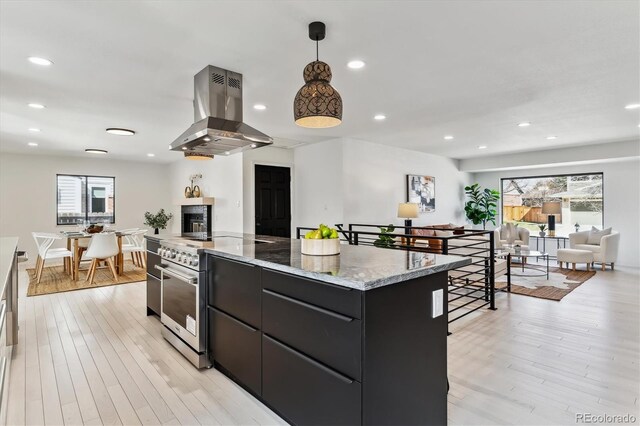 kitchen featuring light wood finished floors, high end stainless steel range oven, island range hood, modern cabinets, and dark cabinetry