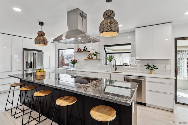 kitchen featuring island exhaust hood, stainless steel appliances, tasteful backsplash, a sink, and modern cabinets