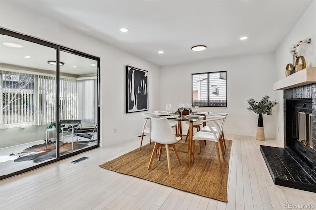 dining area featuring a glass covered fireplace, wood finished floors, visible vents, and recessed lighting