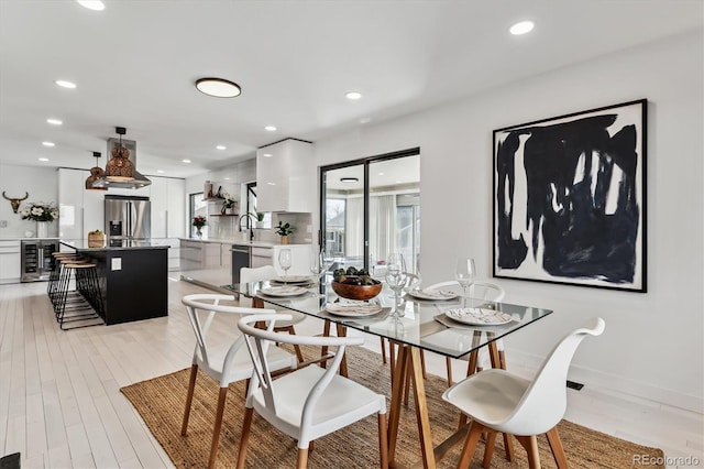 dining space with light wood finished floors, wine cooler, and recessed lighting