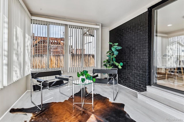 home office with baseboards, brick wall, and wood finished floors