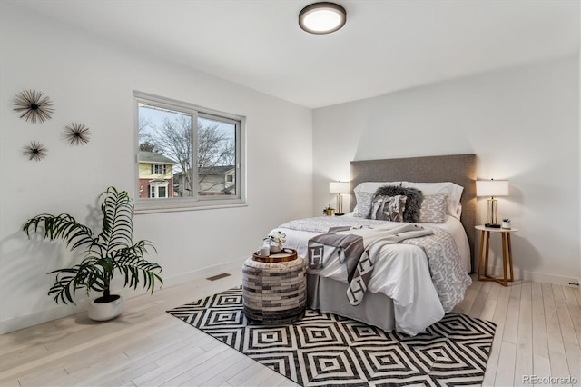 bedroom featuring visible vents, baseboards, and hardwood / wood-style floors