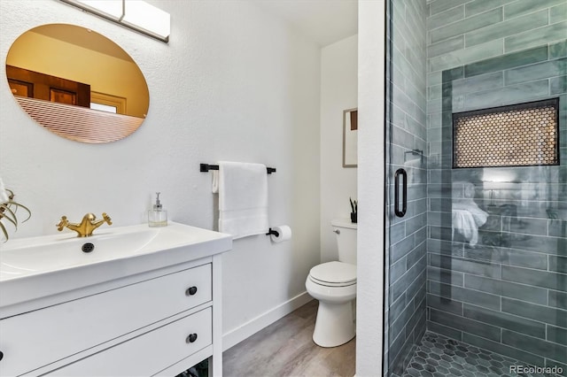 full bath featuring a stall shower, baseboards, toilet, wood finished floors, and vanity