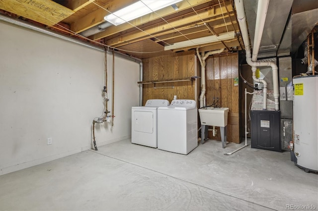 unfinished below grade area featuring water heater, a sink, washing machine and dryer, and heating unit