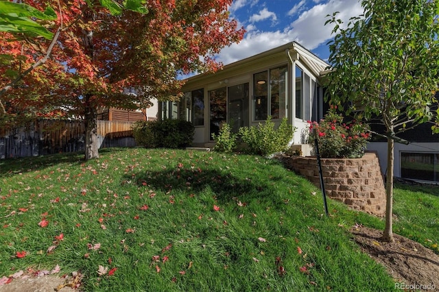 exterior space with a sunroom, a lawn, and fence