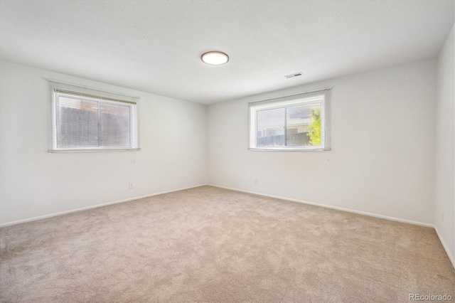 carpeted spare room with visible vents and baseboards