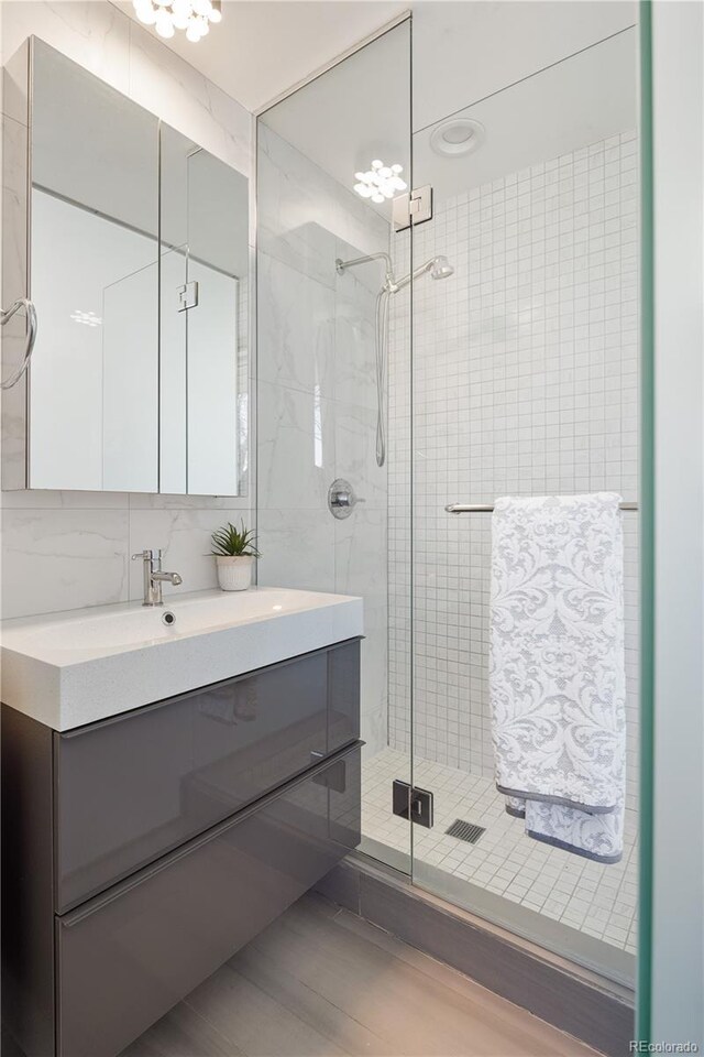 1922 E 18th Ave, Denver, CO 80206 - bathroom with a stall shower, vanity, wood finished floors, backsplash, and tile walls
