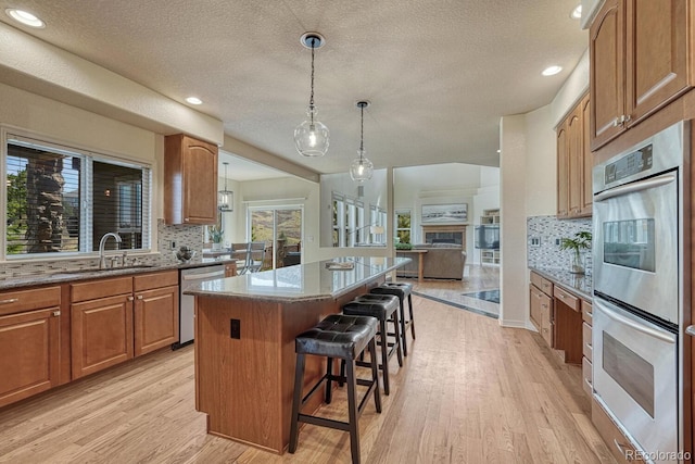580 Eagle Nest Ct, Golden, CO 80401 - kitchen with stainless steel appliances, a sink, a center island, light wood finished floors, and tasteful backsplash