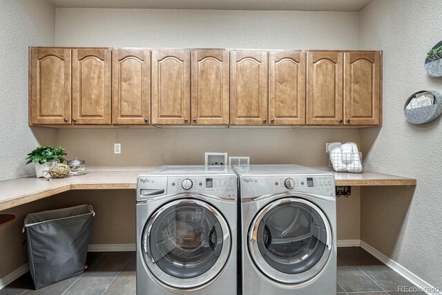 580 Eagle Nest Ct, Golden, CO 80401 - clothes washing area with washing machine and clothes dryer, cabinet space, dark tile patterned flooring, and baseboards