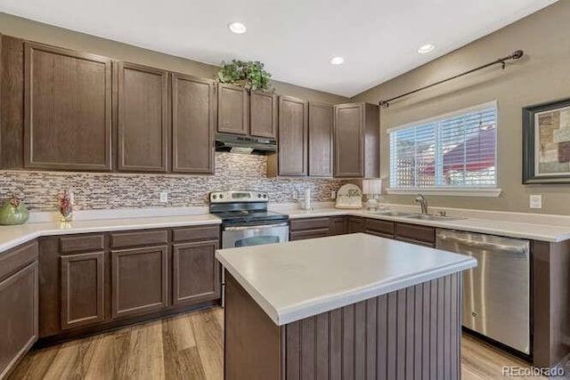 18655 E Garden Pl, Aurora, CO 80015 - kitchen with appliances with stainless steel finishes, under cabinet range hood, a sink, light wood finished floors, and backsplash