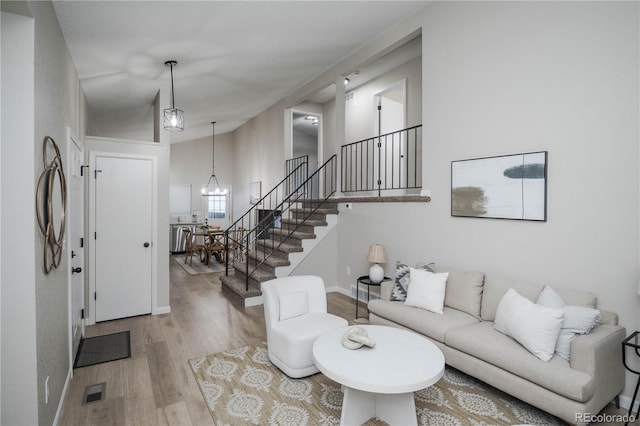 living room with hardwood / wood-style floors, vaulted ceiling, and a notable chandelier