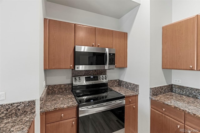 kitchen with stainless steel appliances and dark stone counters