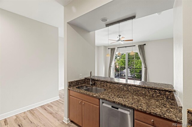 kitchen with sink, dishwasher, light hardwood / wood-style floors, and dark stone counters