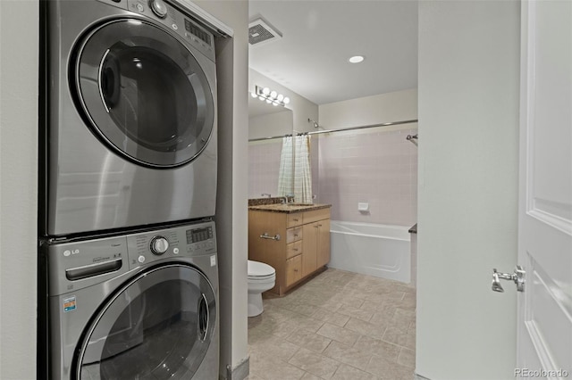 laundry area featuring sink, stacked washer / drying machine, and light tile patterned floors