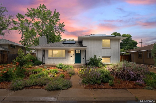 5315 Newland St, Arvada, CO 80002 - split level home with roof mounted solar panels, brick siding, and a chimney