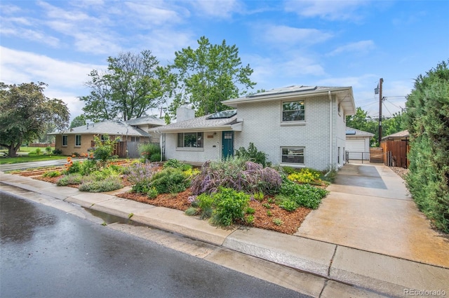 5315 Newland St, Arvada, CO 80002 - tri-level home featuring roof mounted solar panels, a gate, brick siding, and a chimney