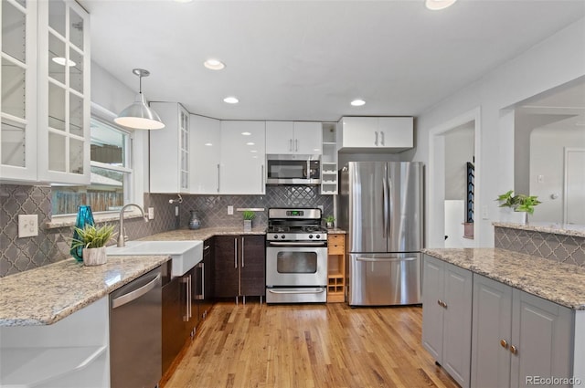 5315 Newland St, Arvada, CO 80002 - kitchen featuring stainless steel appliances, a sink, light wood-style floors, white cabinetry, and decorative backsplash