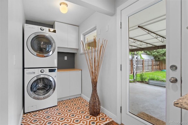 5315 Newland St, Arvada, CO 80002 - washroom featuring stacked washer / dryer, cabinet space, baseboards, and plenty of natural light