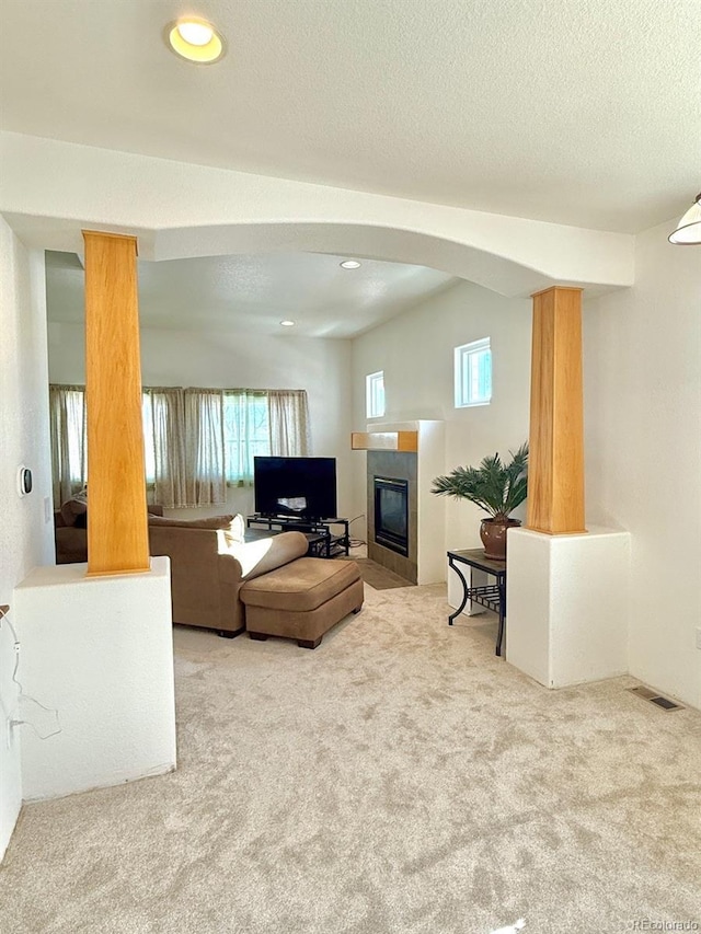 living room with a tiled fireplace, carpet flooring, and a textured ceiling