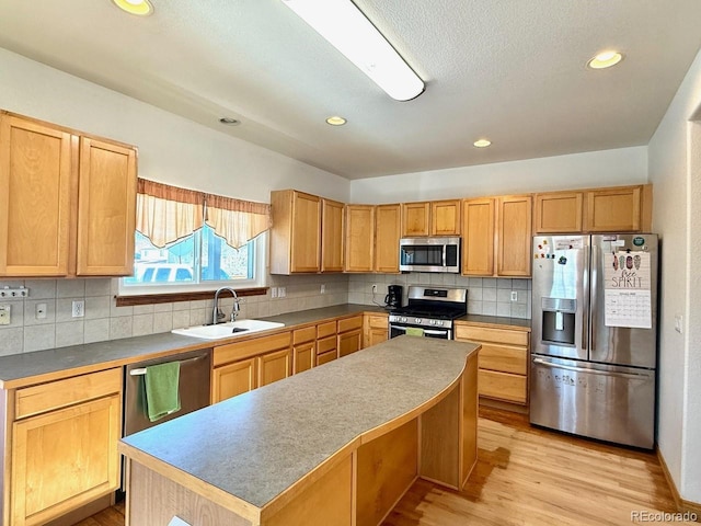 kitchen featuring sink, a center island, stainless steel appliances, light hardwood / wood-style floors, and decorative backsplash