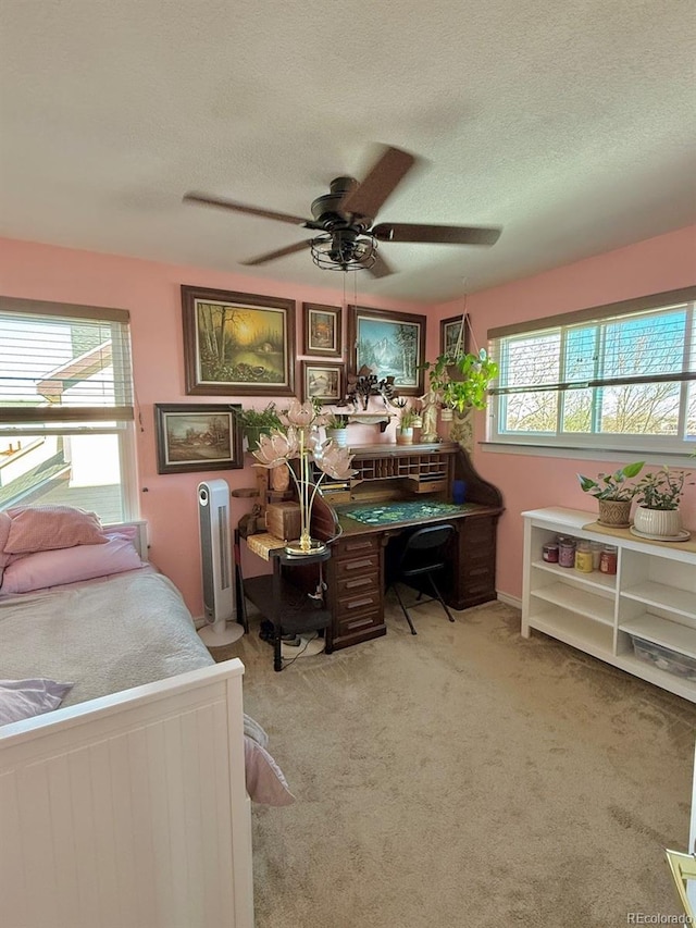 bedroom featuring multiple windows, light colored carpet, a textured ceiling, and ceiling fan