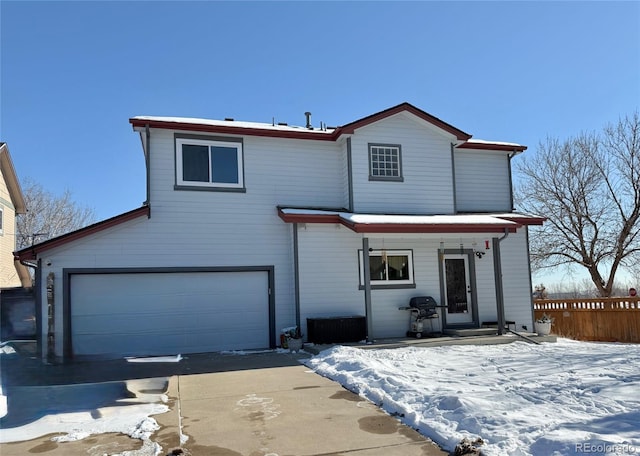 snow covered back of property featuring a garage and a porch