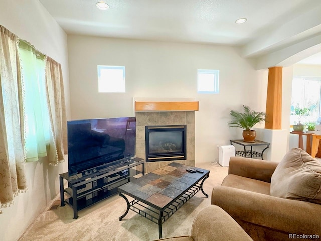 living room featuring a tile fireplace and light carpet