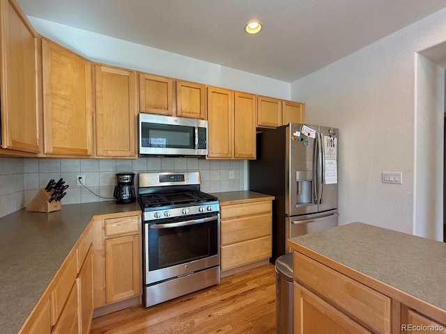 kitchen with light brown cabinetry, backsplash, stainless steel appliances, and light wood-type flooring