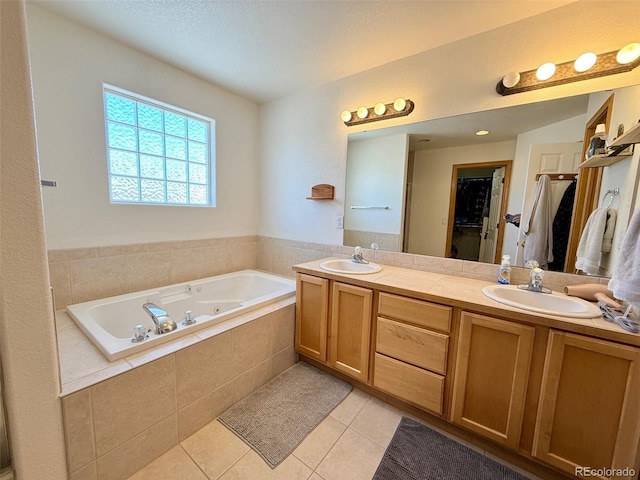 bathroom with tile patterned flooring, vanity, and tiled tub