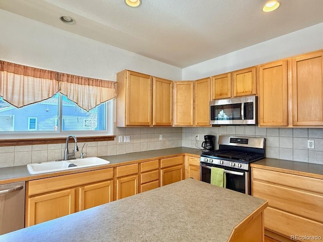 kitchen featuring appliances with stainless steel finishes, light brown cabinetry, sink, and backsplash